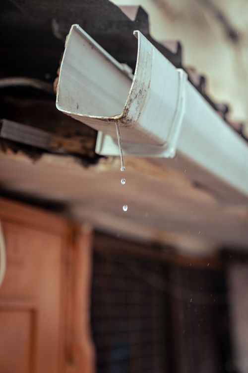 Rainwater dripping from a clean white gutter